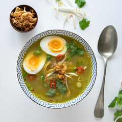 Top down view of a vegetarian Indonesian soup, traditionally made with chicken called soto ayam on white background