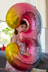 A Cute Baby Girl Holding A Number Three Balloon