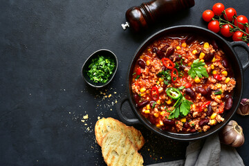 Chili con carne - traditional mexican minced meat and vegetables stew in tomato sauce in a cast iron pan . Top view with copy space.
