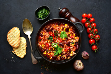 Chili con carne - traditional mexican minced meat and vegetables stew in tomato sauce in a cast iron pan . Top view with copy space.