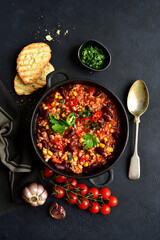 Chili con carne - traditional mexican minced meat and vegetables stew in tomato sauce in a cast iron pan . Top view with copy space.