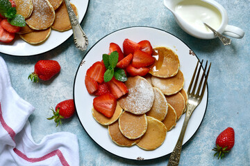 Delicious tiny pancakes with fresh strawberry. Top view with copy space.