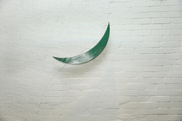 White wall painted with paint with green moon decoration attached