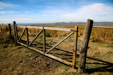 Country gate. Landscape of field and mountains. Nature. Blue sky with clouds. Grasslands Green. Outdoor. Access door. Chains. Mountains of Cordoba. Argentina. Fence.
