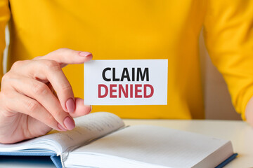 claim denied written on a paper card in woman hand, concept
