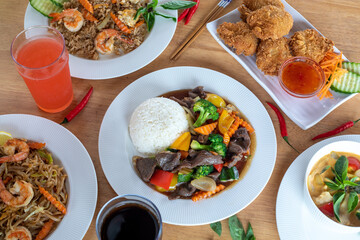 A top-down view of several varieties of  Thai food with pares chopsticks in hand with wood background. Bamboo shoots, Glass noodles, Carrot, Oyster sauce, Rice, shrimp, Cabbage, onions, strong basil, 
