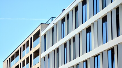Fragment of a modern white office building. Facade of modern building. Reflection of sky in windows. Abstract blue architectural background.