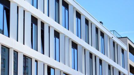 Fragment of a modern white office building. Facade of modern building. Reflection of sky in windows. Abstract blue architectural background.