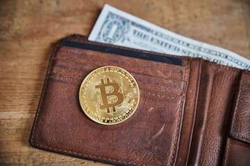 Closeup of a golden bitcoin medal in a leather purse. Crypto wallet with golden bitcoin.