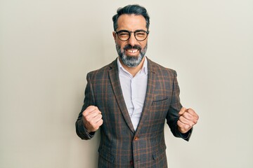 Middle age man with beard and grey hair wearing business jacket and glasses excited for success...