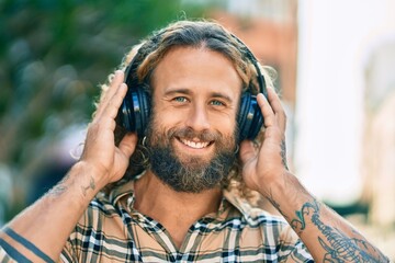 Young caucasian man smiling happy using headphones at the park.