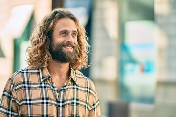 Obraz premium Young caucasian man with long hair smiling happy at the city.