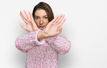 Young caucasian girl wearing wool winter sweater rejection expression crossing arms and palms doing...