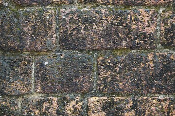 Closeup of ancient stone wall with dark lichen and soot stains abstract horizontal background texture