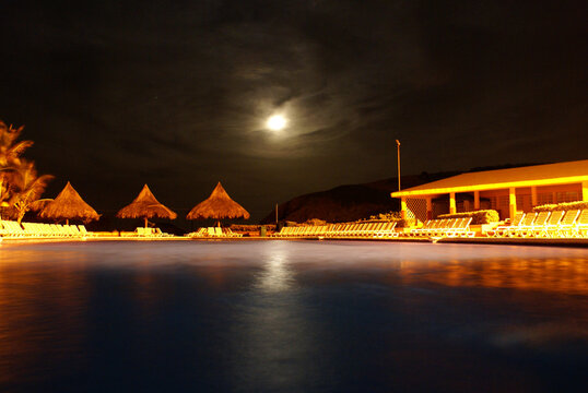 La luna en el cielo despejado frente a una piscina en la playa
