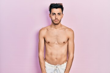 Fototapeta premium Young hispanic man wearing swimwear shirtless depressed and worry for distress, crying angry and afraid. sad expression.