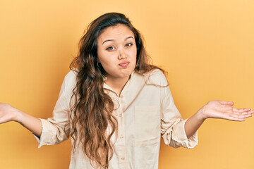 Young hispanic girl wearing casual clothes clueless and confused with open arms, no idea and...