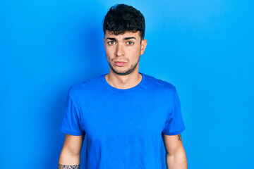 Young hispanic man wearing casual blue t shirt skeptic and nervous, frowning upset because of problem. negative person.