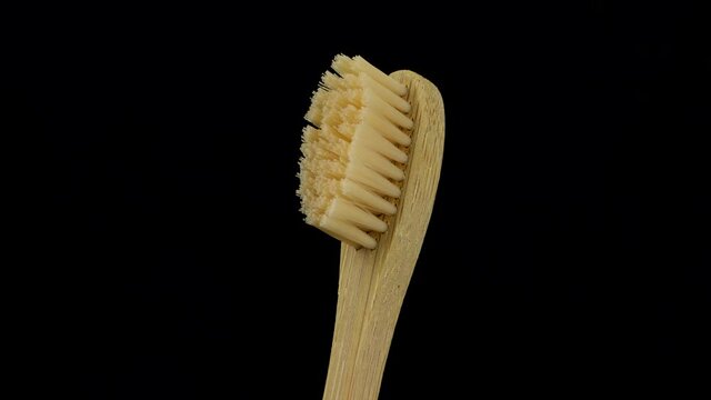 Wooden (bamboo) toothbrush on black background rotating