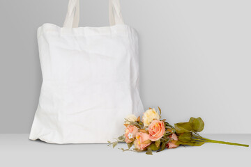 Mockup white tote bag fabric for shopping and flower on desk, mock up canvas bag textile with...
