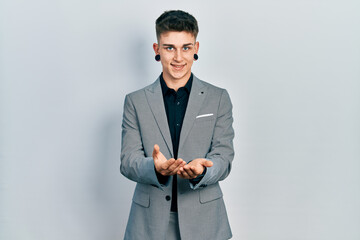 Young caucasian boy with ears dilation wearing business jacket smiling with hands palms together receiving or giving gesture. hold and protection