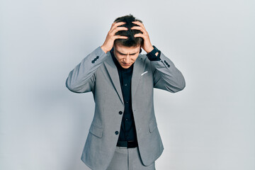 Young caucasian boy with ears dilation wearing business jacket suffering from headache desperate and stressed because pain and migraine. hands on head.