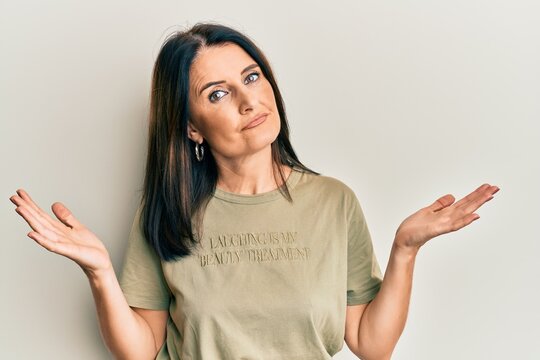 Middle age brunette woman wearing casual clothes clueless and confused with open arms, no idea and doubtful face.