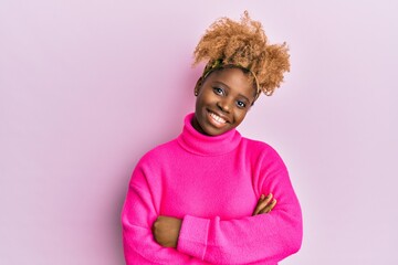 Young african woman with afro hair wearing casual winter sweater happy face smiling with crossed arms looking at the camera. positive person.