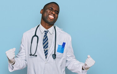 Young african american man wearing doctor uniform and stethoscope very happy and excited doing winner gesture with arms raised, smiling and screaming for success. celebration concept.