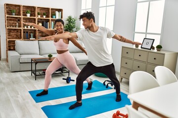 Young latin sporty couple smiling happy training at home.