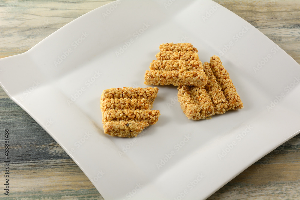 Wall mural pieces of broken sugar glazed sesame brittle bar on white snack plate