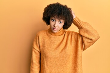 Young hispanic girl wearing wool winter sweater confuse and wonder about question. uncertain with doubt, thinking with hand on head. pensive concept.