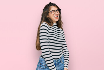 Young beautiful teen girl wearing casual clothes and glasses winking looking at the camera with sexy expression, cheerful and happy face.