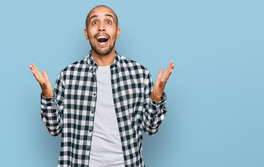 Hispanic adult man wearing casual clothes celebrating crazy and amazed for success with arms raised...
