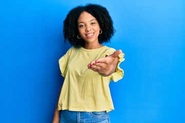 Young african american girl wearing casual clothes smiling friendly offering handshake as greeting and welcoming. successful business.