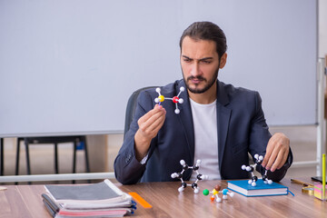 Young male teacher physicist in the classroom