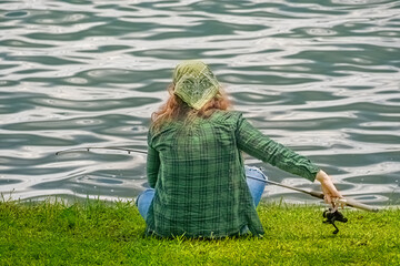 Woman baits a fishing pole for fishing on the shore of a lake.