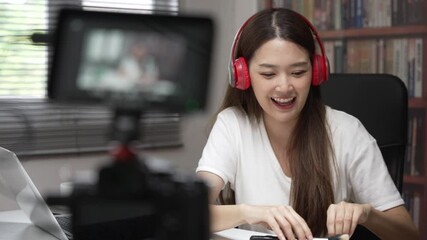Medium close up shot of Asian young lady talking on cosmetics while holding a brush on and demonstrate during record video. Woman making video live tutorial for her cosmetics blog. Cosmetic reviewer.