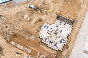 construction workers pouring wet concrete into floor slab by concrete pump machine on a building site. drone photo