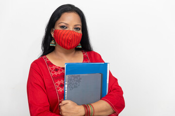 Portrait of an Indian woman standing against white wall,, female holding files and folders, woman wearing Covid 19 protection mask.