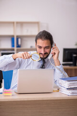 Young businessman employee holding loupe in auditing concept