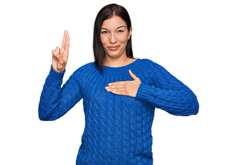 Young hispanic woman wearing casual clothes smiling swearing with hand on chest and fingers up,...