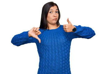 Young hispanic woman wearing casual clothes doing thumbs up and down, disagreement and agreement...