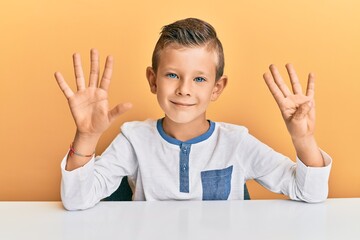 Adorable caucasian kid wearing casual clothes sitting on the table showing and pointing up with...