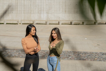 Two young friends chatting relaxed in a concrete square. Friendship concept, casual photography.