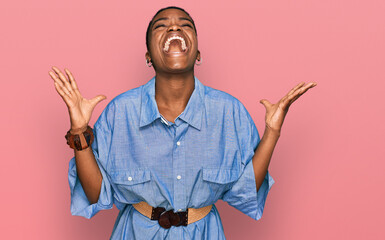 Young african american woman wearing casual clothes celebrating mad and crazy for success with arms...