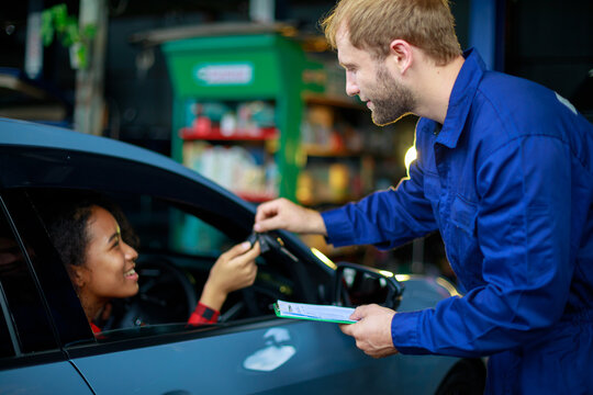 A female customer get car key from mechanic engineer.
