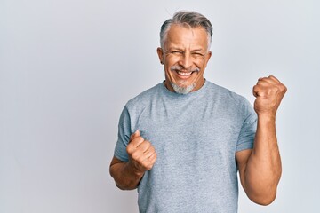 Middle age grey-haired man wearing casual clothes celebrating surprised and amazed for success with arms raised and eyes closed