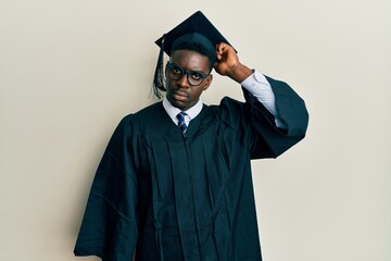 Handsome black man wearing graduation cap and ceremony robe confuse and wondering about question....