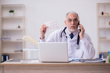 Old male doctor cardiologist working in the clinic